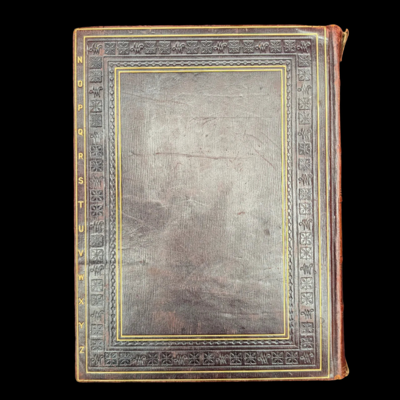 Vintage leather-bound book with decorative cover on a black background