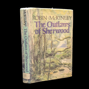 A hardcover edition of 'The Outlaws of Sherwood' by Robin McKinley with a green and beige cover, featuring an illustration of a forest scene with a tree in the foreground and a building in the background.