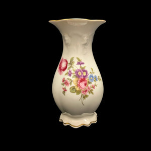 A beige ceramic vase with a floral pattern, featuring pink and blue flowers, displayed against a black background.