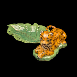 A porcelain serving tray featuring a stylized jaguar on a green leaf-shaped base, with the word 'WELL' written on the leaf.