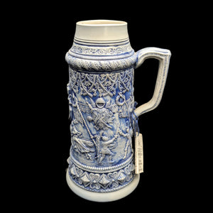 A large ceramic stein with blue and white decorative patterns, featuring detailed relief imagery.