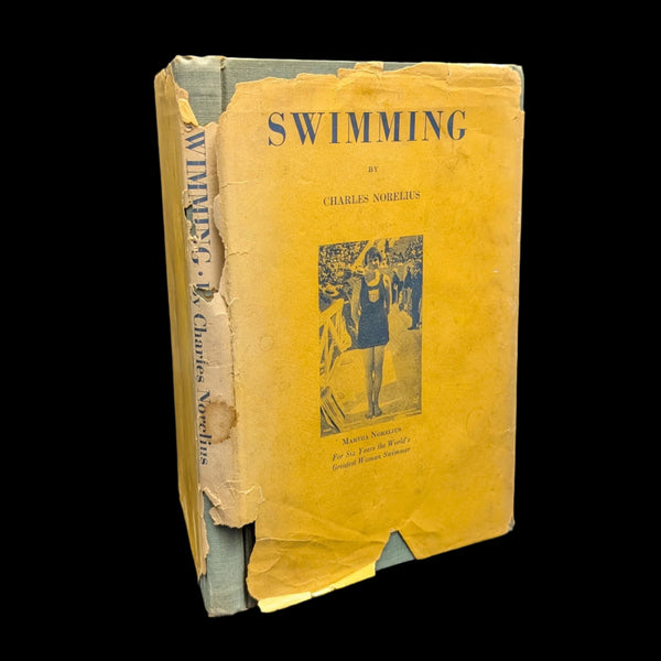 An old edition of 'Swimming' signed by Charles Norelius with visible wear and damage on the cover.