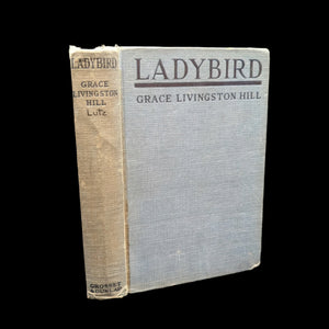 A dust jacket of a book titled 'Ladybird' by Grace Livingston Hill, showing signs of wear and a previous owner's inscription.