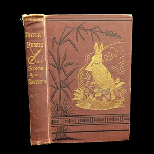 Cover of the book 'Uncle Remus, His Songs And Sayings', featuring a gold illustration of a rabbit on a brown background with text and decorative elements.