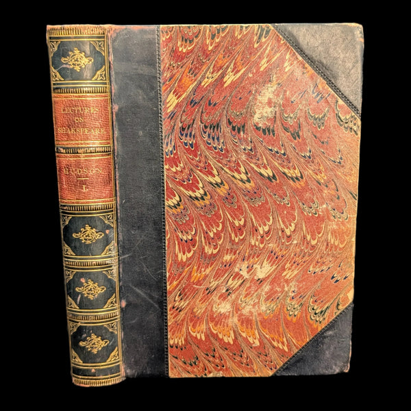 An old book with a decorative cover featuring red and gold colors, titled 'Lectures On Shakespeare, In Two Volumes, 1848'. The book appears to be leather bound.