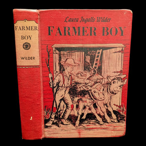 A hardcover copy of 'Farmer Boy' by Laura Ingall's Wilder, with illustrated cover showing two children on a farm.
