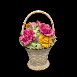 A Royal Albert porcelain music box in the shape of a basket with a handle, overflowed with vibrant roses in pink, yellow, and green colors.