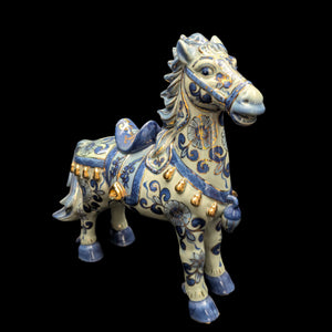A vintage porcelain horse figurine with blue and white patterns and gold accents.