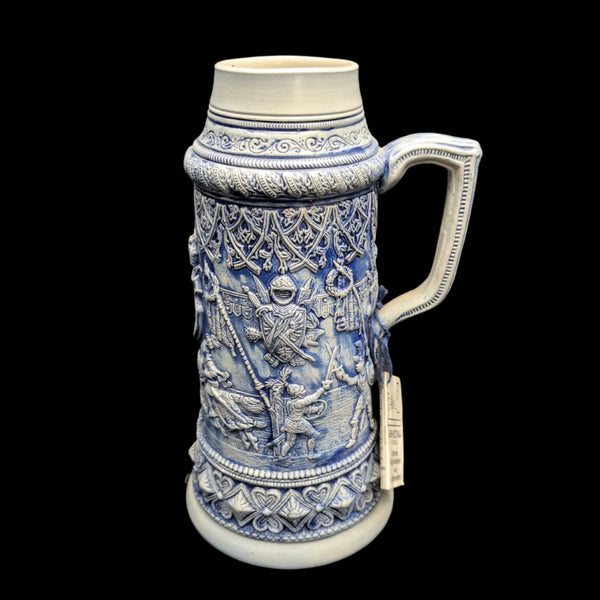 A large ceramic stein with blue and white decorative patterns, featuring detailed relief imagery.