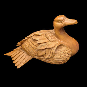 A vintage hand-carved wooden swan sculpture with intricate feather details, isolated on a black background.